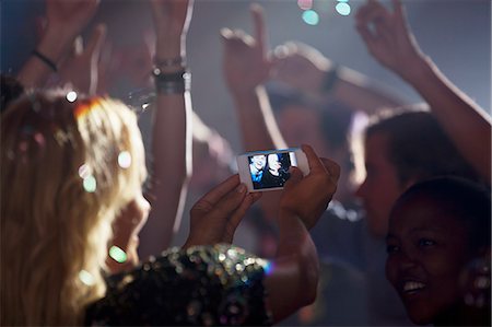 Woman with camera phone photographing friends on dance floor of nightclub Foto de stock - Sin royalties Premium, Código: 6113-06498600