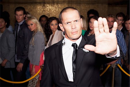 Portrait of bouncer with arm outstretched outside nightclub Foto de stock - Sin royalties Premium, Código: 6113-06498623