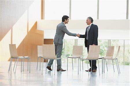 simsearch:6113-06497907,k - Chairs surrounding businessmen shaking hands Stock Photo - Premium Royalty-Free, Code: 6113-06498779