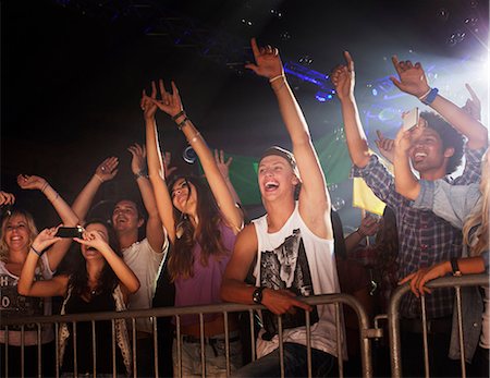 Enthusiastic crowd with arms raised behind railing at concert Photographie de stock - Premium Libres de Droits, Code: 6113-06498708