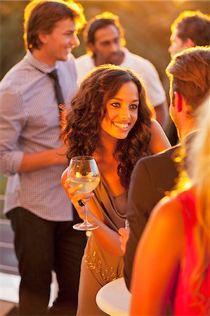 Smiling woman with wine glass talking to man on sunny balcony Stock Photo - Premium Royalty-Free, Code: 6113-06498711