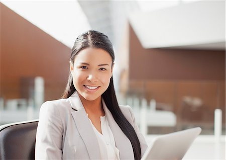 filipina - Portrait of smiling businesswoman using digital tablet in office Stock Photo - Premium Royalty-Free, Code: 6113-06498891