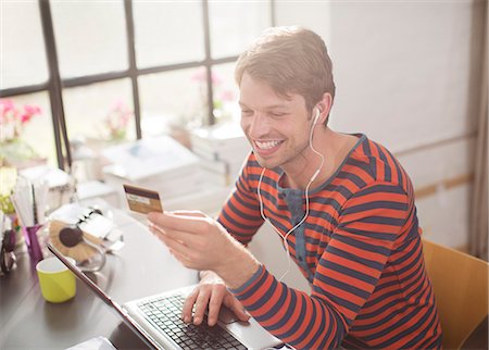 shopping mobile - Man in headphones shopping on laptop Stock Photo - Premium Royalty-Free, Code: 6113-06625563