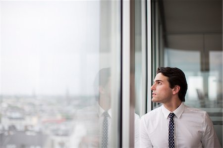 Businessman looking out office window Stock Photo - Premium Royalty-Free, Code: 6113-06625702