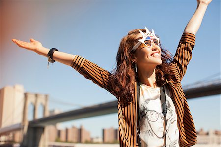 Woman in novelty sunglasses standing by urban bridge Stock Photo - Premium Royalty-Free, Code: 6113-06626160