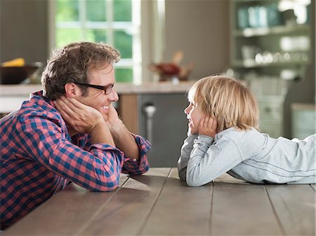 simsearch:6113-06626289,k - Father and son admiring each other at table Stock Photo - Premium Royalty-Free, Code: 6113-06626298