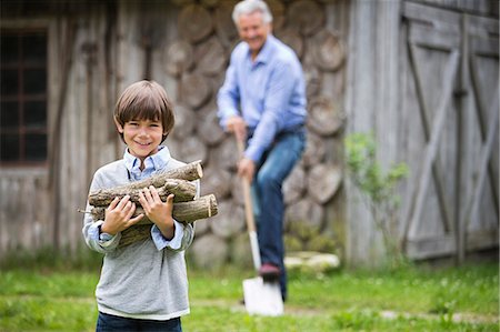 Boy carrying pile of firewood outdoors Stock Photo - Premium Royalty-Free, Code: 6113-06626303