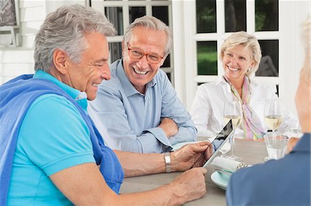 seniors socializing - Friends using digital tablet together Photographie de stock - Premium Libres de Droits, Code: 6113-06626302