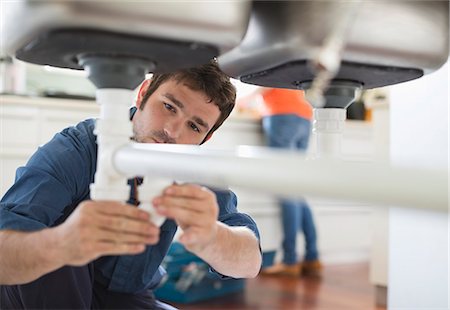 Plumber working on pipes under sink Stock Photo - Premium Royalty-Free, Code: 6113-06753207