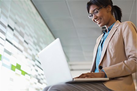 sitting on laps - Businesswoman using laptop in office Stock Photo - Premium Royalty-Free, Code: 6113-06753435