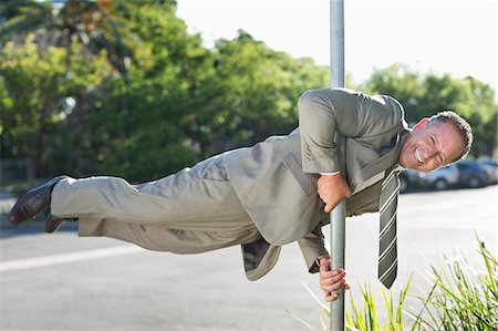 ridiculous - Businessman balancing on pole on city street Stock Photo - Premium Royalty-Free, Code: 6113-06753508