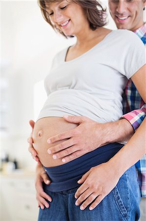 pregnant belly button - Man holding pregnant girlfriend's belly Stock Photo - Premium Royalty-Free, Code: 6113-06753679