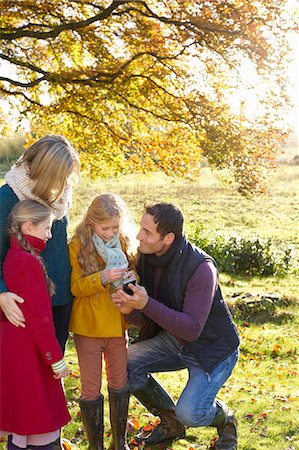 Family using cell phone together outdoors Stock Photo - Premium Royalty-Free, Code: 6113-06720309