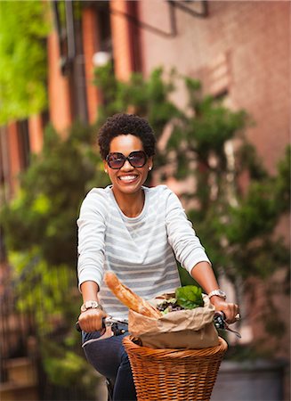 riding bike with basket - Woman riding bicycle on city street Stock Photo - Premium Royalty-Free, Code: 6113-06720438