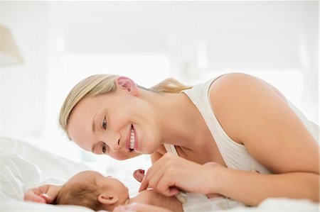 simsearch:6113-07543205,k - Mother cradling newborn infant on bed Stock Photo - Premium Royalty-Free, Code: 6113-06720585