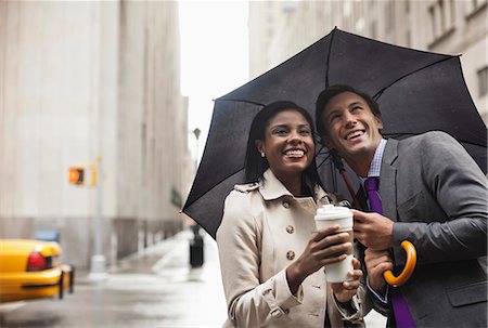 Business people holding umbrella on city street Stock Photo - Premium Royalty-Free, Code: 6113-06720505