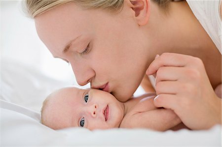 simsearch:6113-06720631,k - Mother kissing newborn baby on bed Foto de stock - Sin royalties Premium, Código: 6113-06720664