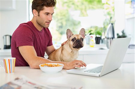 pet owners and their pets - Man on laptop petting dog in kitchen Stock Photo - Premium Royalty-Free, Code: 6113-06720952