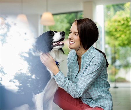 simsearch:6113-06720984,k - Smiling woman petting dog indoors Foto de stock - Sin royalties Premium, Código: 6113-06720977