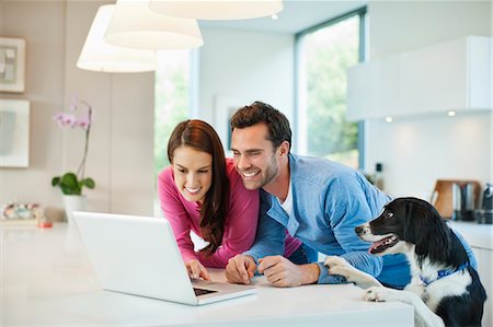 Couple using laptop with dog at table Foto de stock - Sin royalties Premium, Código: 6113-06720998