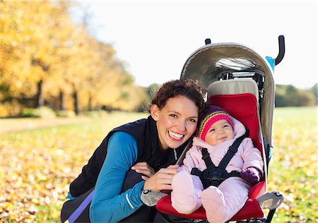 Woman smiling with baby in stroller Stock Photo - Premium Royalty-Free, Code: 6113-06721323