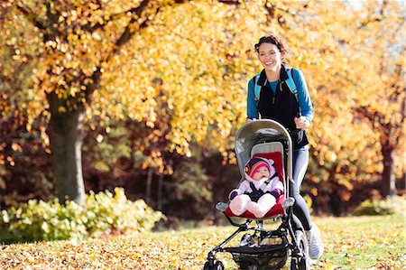 Woman running with baby stroller in park Stock Photo - Premium Royalty-Free, Code: 6113-06721321