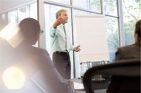 Businessman gesturing at flipchart in meeting Stock Photo - Premium Royalty-Free, Code: 6113-06899000