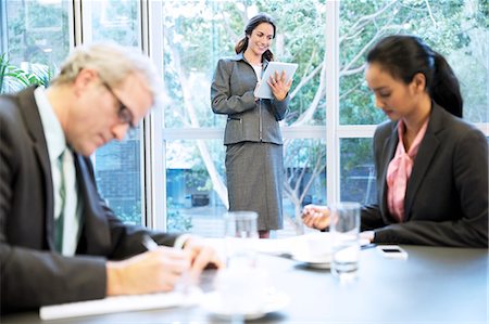 Smiling woman using digital tablet at window in conference room Stock Photo - Premium Royalty-Free, Code: 6113-06899160