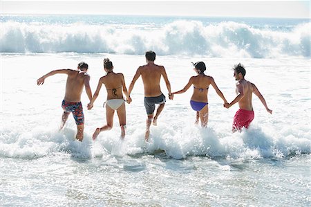 simsearch:6113-06899255,k - Friends holding hands and splashing in ocean Stock Photo - Premium Royalty-Free, Code: 6113-06899225