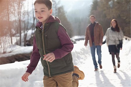 simsearch:6113-06899473,k - Parents watching boy run in snowy lane Stock Photo - Premium Royalty-Free, Code: 6113-06899452