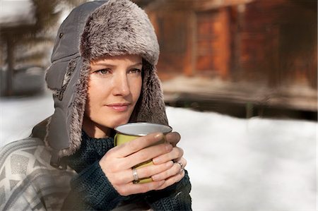 simsearch:6113-06899345,k - Pensive woman in fur hat drinking coffee outside cabin Stock Photo - Premium Royalty-Free, Code: 6113-06899470