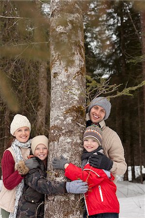simsearch:6113-06899473,k - Portrait of happy family hugging tree trunk in snowy woods Stock Photo - Premium Royalty-Free, Code: 6113-06899488