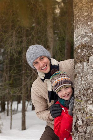 simsearch:6113-06899345,k - Portrait of happy father and son behind tree trunk in snowy woods Stock Photo - Premium Royalty-Free, Code: 6113-06899498