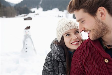 Close up of happy couple in snowy field with snowman Stock Photo - Premium Royalty-Free, Code: 6113-06899408