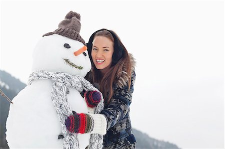 Portrait of happy woman hugging snowman Stock Photo - Premium Royalty-Free, Code: 6113-06899418