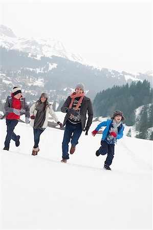 Happy family running in snowy field Stock Photo - Premium Royalty-Free, Code: 6113-06899432