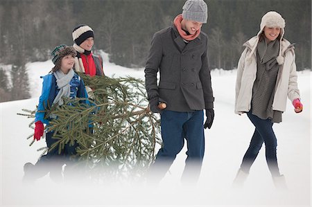 simsearch:6113-06899473,k - Happy family carrying fresh Christmas tree in snowy field Stock Photo - Premium Royalty-Free, Code: 6113-06899434