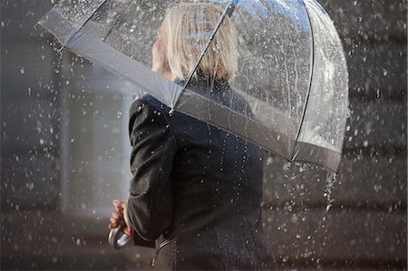 Businesswoman under umbrella in rain Stock Photo - Premium Royalty-Free, Code: 6113-06899547