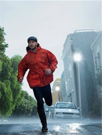 Man in raincoat running in rain Stock Photo - Premium Royalty-Free, Code: 6113-06899564
