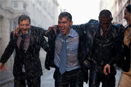 Happy businessmen walking in rainy street Stock Photo - Premium Royalty-Free, Code: 6113-06899593