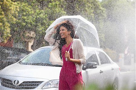 Happy woman with umbrella in rain Photographie de stock - Premium Libres de Droits, Code: 6113-06899597