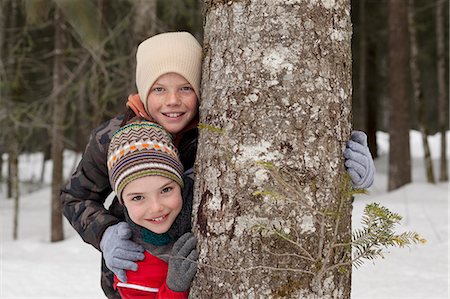simsearch:6113-06899345,k - Portrait of happy boys behind tree trunk in snowy woods Stock Photo - Premium Royalty-Free, Code: 6113-06899501