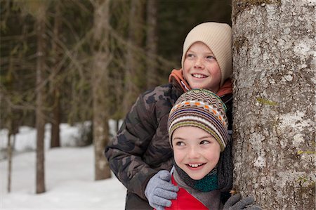 simsearch:6113-06899345,k - Happy boys leaning against tree trunk in snowy woods Stock Photo - Premium Royalty-Free, Code: 6113-06899510