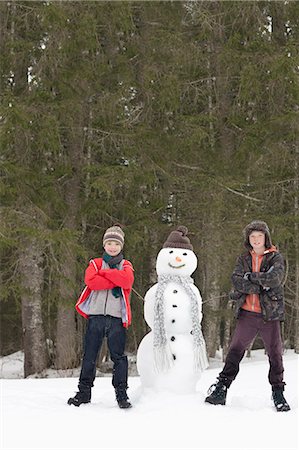 simsearch:6113-06899345,k - Portrait of confident boys next to snowman in woods Stock Photo - Premium Royalty-Free, Code: 6113-06899519