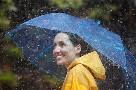 Happy woman with umbrella in rain Stock Photo - Premium Royalty-Free, Code: 6113-06899537