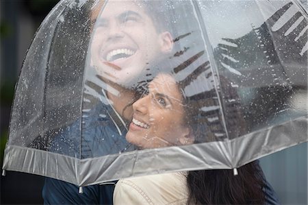 simsearch:6113-06899628,k - Happy couple under umbrella looking up at rain Stock Photo - Premium Royalty-Free, Code: 6113-06899648