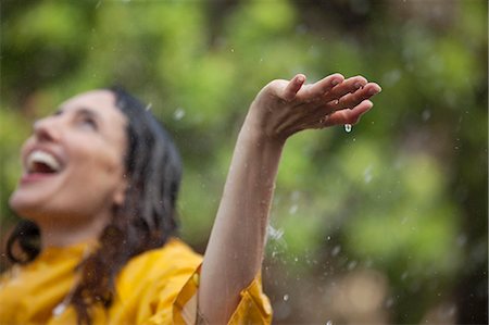 Enthusiastic woman standing with arms outstretched and head back in rain Foto de stock - Sin royalties Premium, Código: 6113-06899657