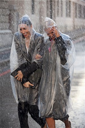 simsearch:6113-06899628,k - Businesswomen in ponchos walking in rainy street Stock Photo - Premium Royalty-Free, Code: 6113-06899610