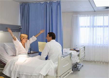 simsearch:6113-06908281,k - Doctor talking to cheering patient in hospital room Stock Photo - Premium Royalty-Free, Code: 6113-06908305