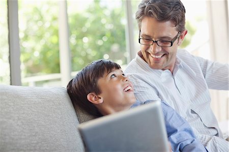 Father and son using tablet computer on sofa Stock Photo - Premium Royalty-Free, Code: 6113-06908724